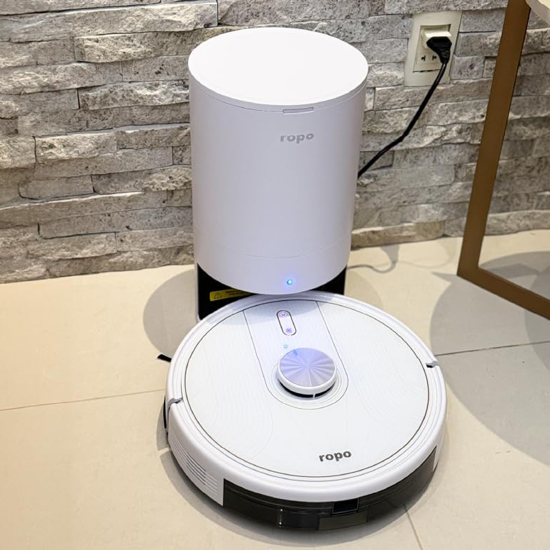 Robô aspirador Ropo Glass 5 Pro preto com estação autolimpante compacta em ambiente doméstico.